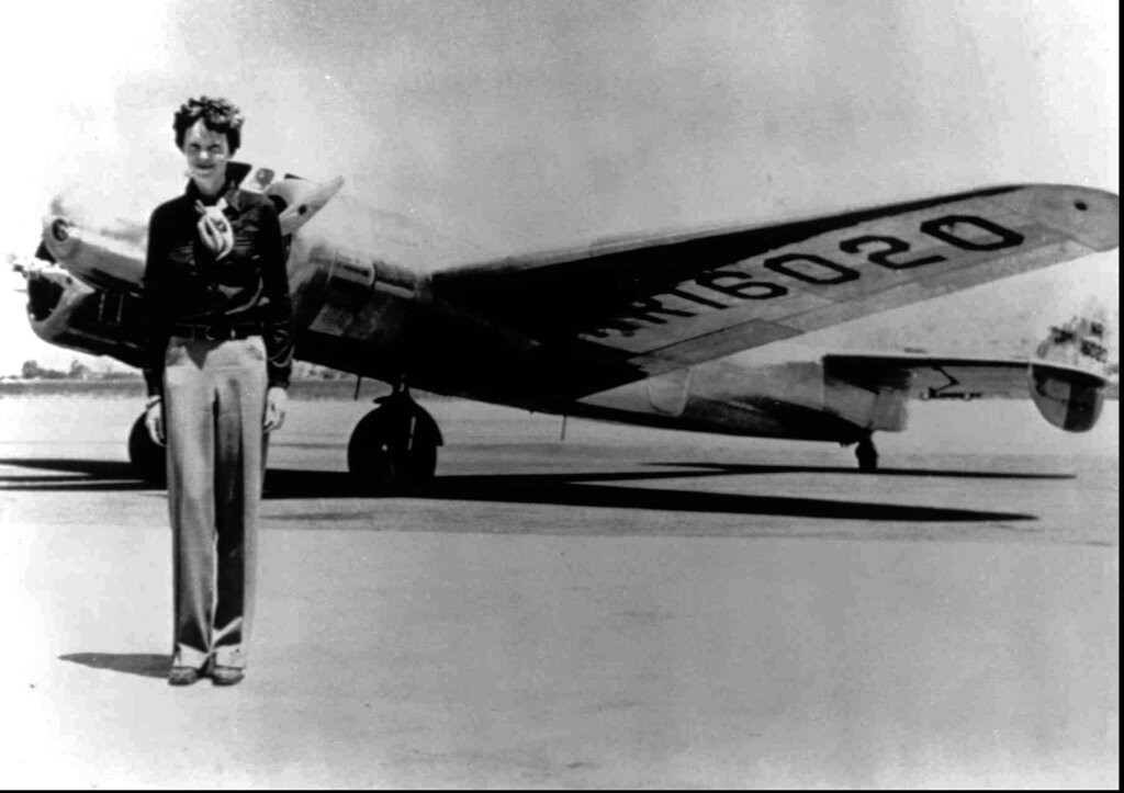 Amelia Earhart stands next to a Lockheed Electra 10E