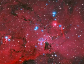 Το Hubble της NASA απαθανατίζει ένα κατακόκκινο νέφος που λάμπει από λευκά και γαλάζια άστρα