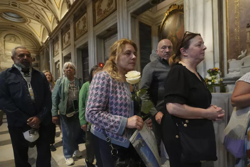 A woman holds a white rose as she waits in line to pay her respects to the tomb of Pope Francis inside St. Mary Major Basilica in Rome