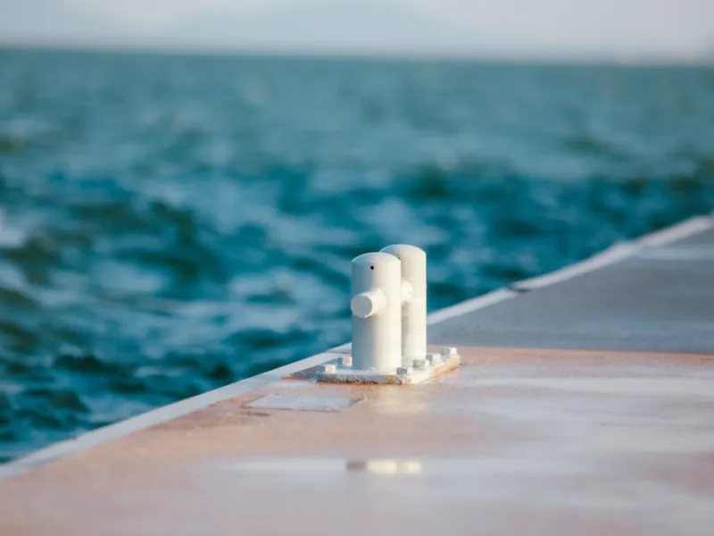 White steel cleat bollard on a dock for tying up boats, maritime nautical concept with ocean